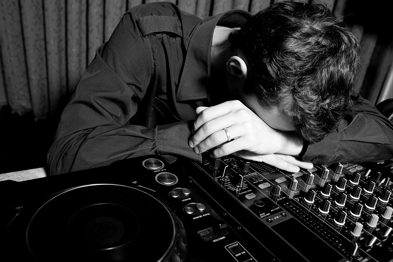 Cheap Wedding DJs: Why Low Price Costs More — exhausted DJ at mixer during event